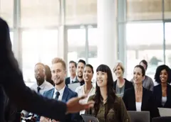 Speaker di spalle davanti a un pubblico sorridente durante evento relazionale