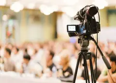 Fotocamera in primo piano durante un evento dedicato alle relazioni, con il pubblico sullo sfondo