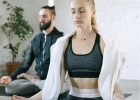 Uomo e donna in posizione yoga per gestione ansia e tecniche di rilassamento efficaci